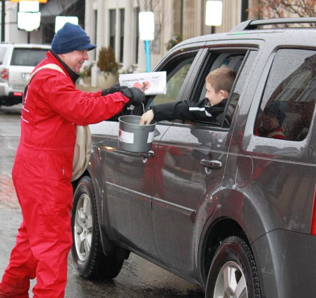 man handing paper to small boy in a car